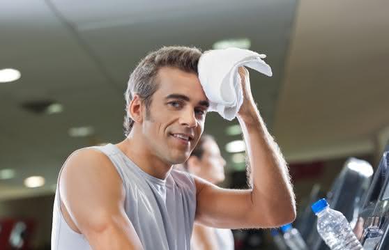 Man Wiping Sweat With Towel At Health Club